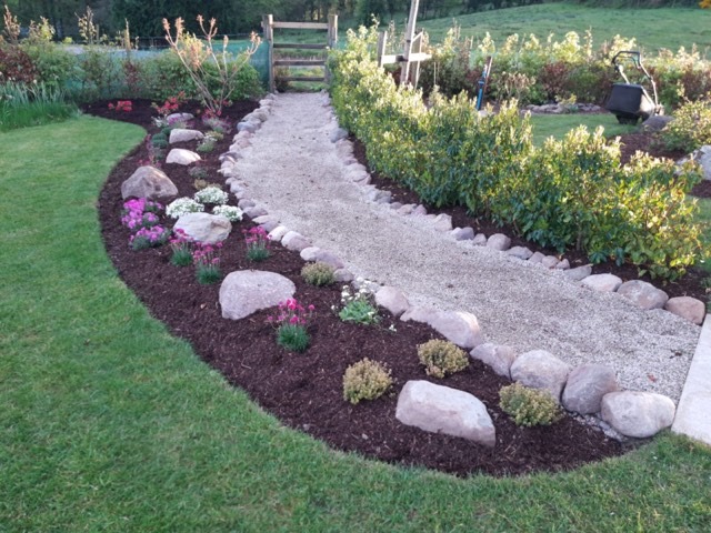 https://davidperrygardens.com/wp-content/uploads/2020/07/Incorporating-natural-glacial-rocks-into-a-flower-bed-and-edging-a-garden-path-with-small-rocks.jpg